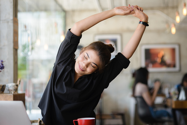 woman stretching her back when sitting at a cafe